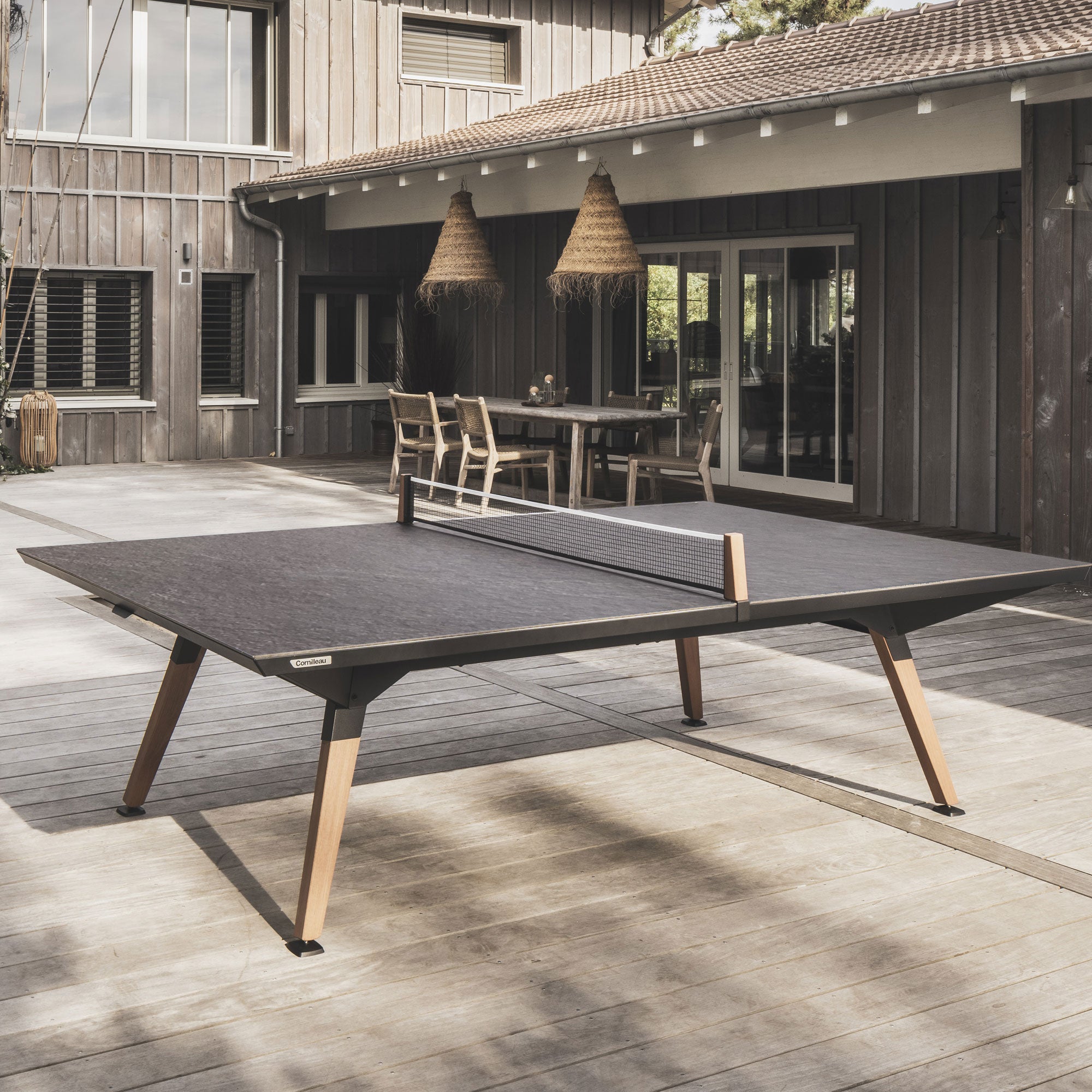 Outdoor ping pong table in a modern patio setting with a house in the background